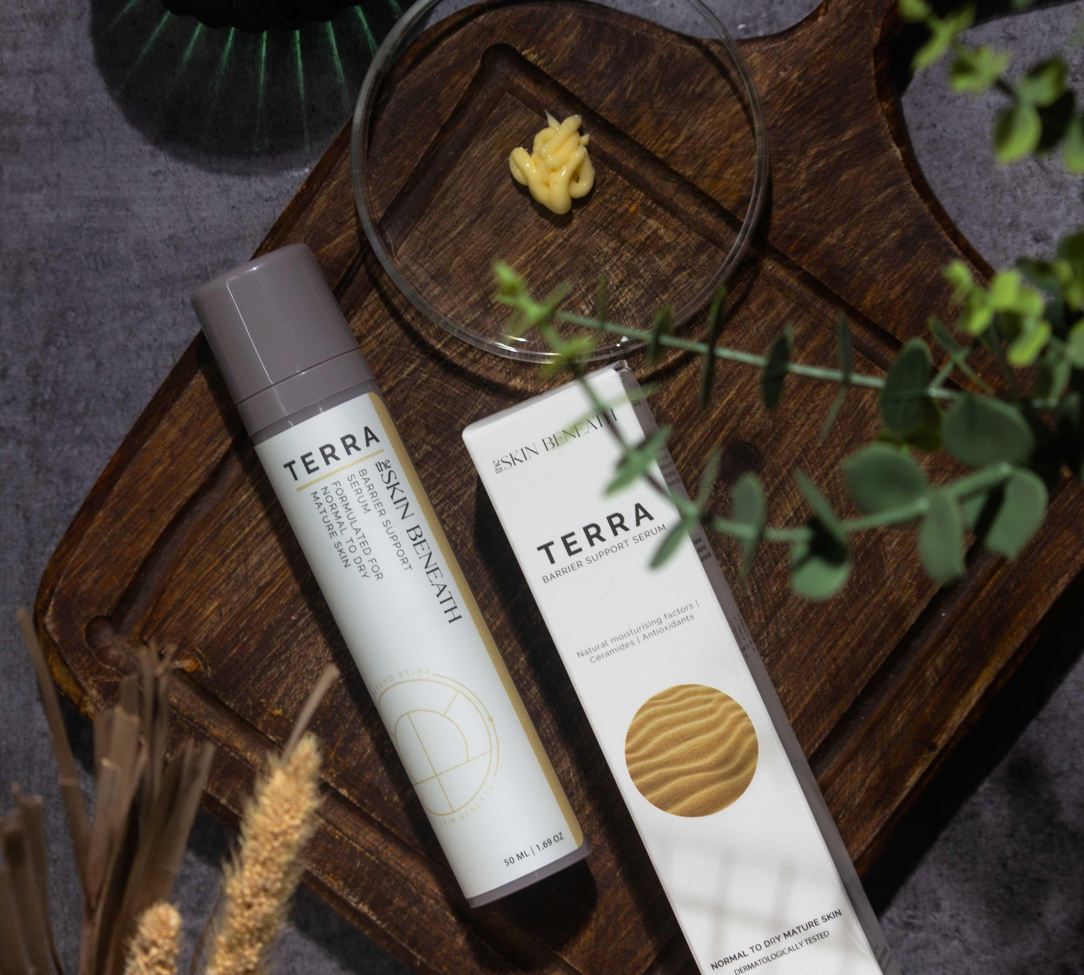 Terra barrier-repair serum bottle on vintage wooden tray with moody shadows, captured as part of an emotional skincare ritual
