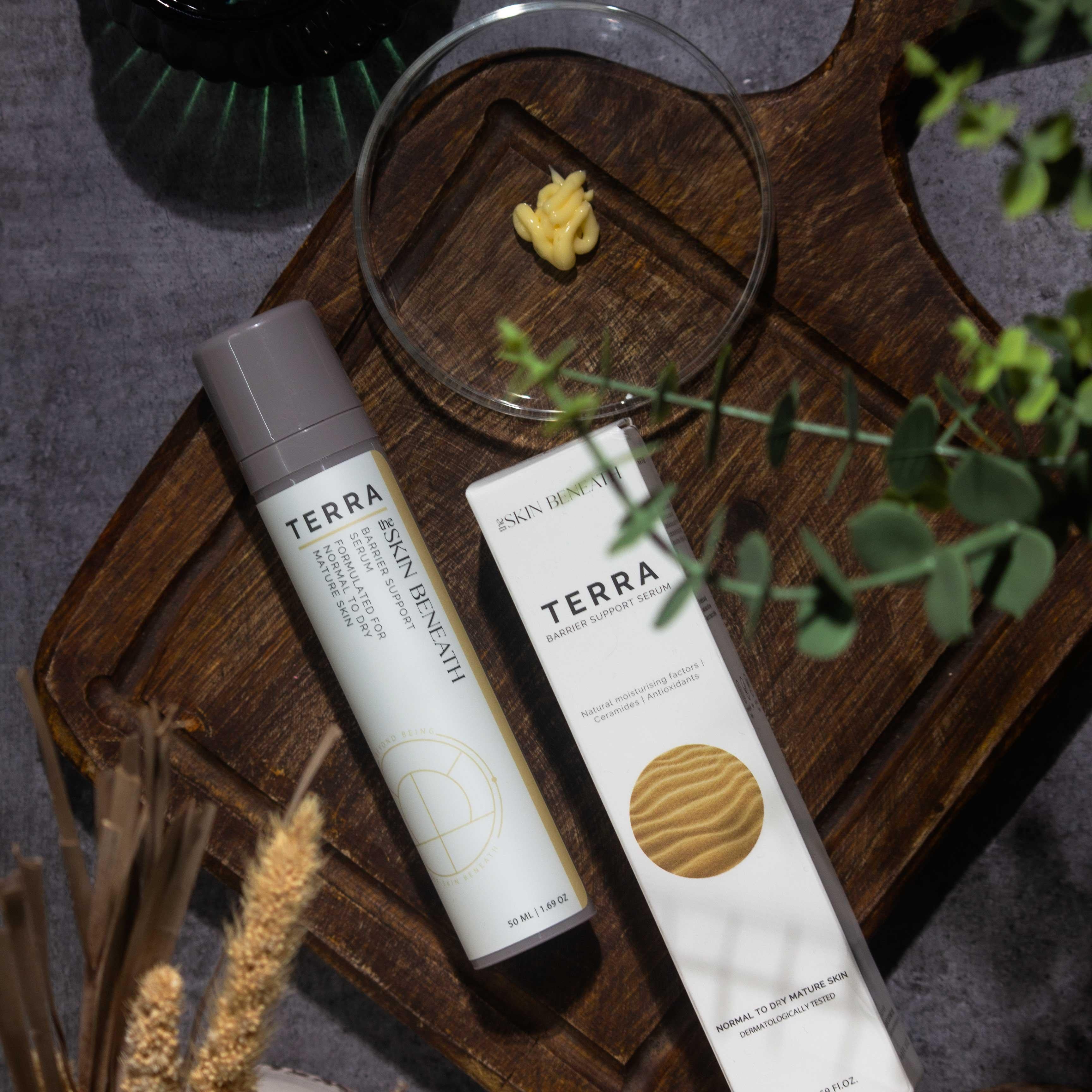 Terra barrier-repair serum bottle on vintage wooden tray with moody shadows, captured as part of an emotional skincare ritual