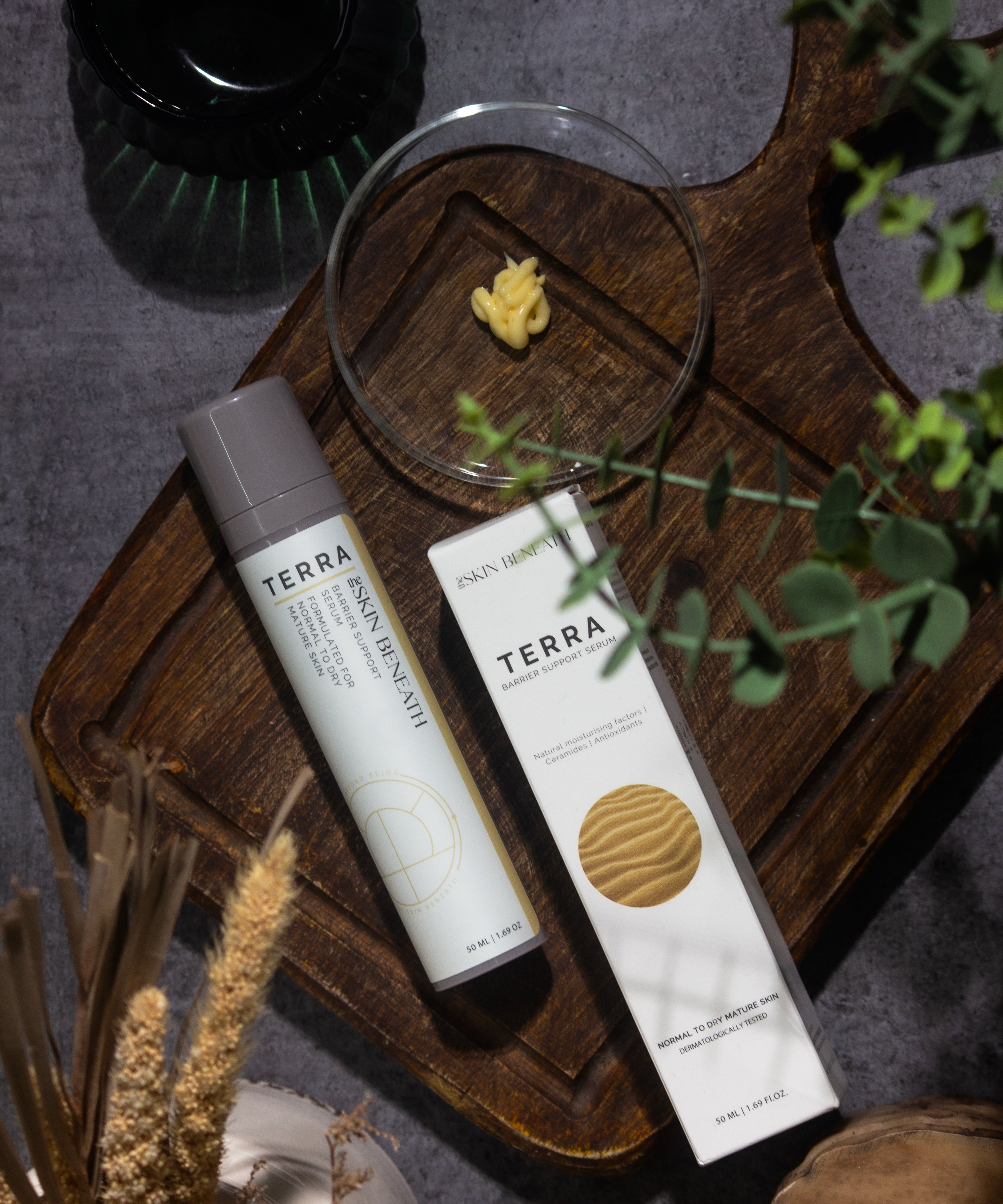 Terra barrier-repair serum bottle on vintage wooden tray with moody shadows, captured as part of an emotional skincare ritual
