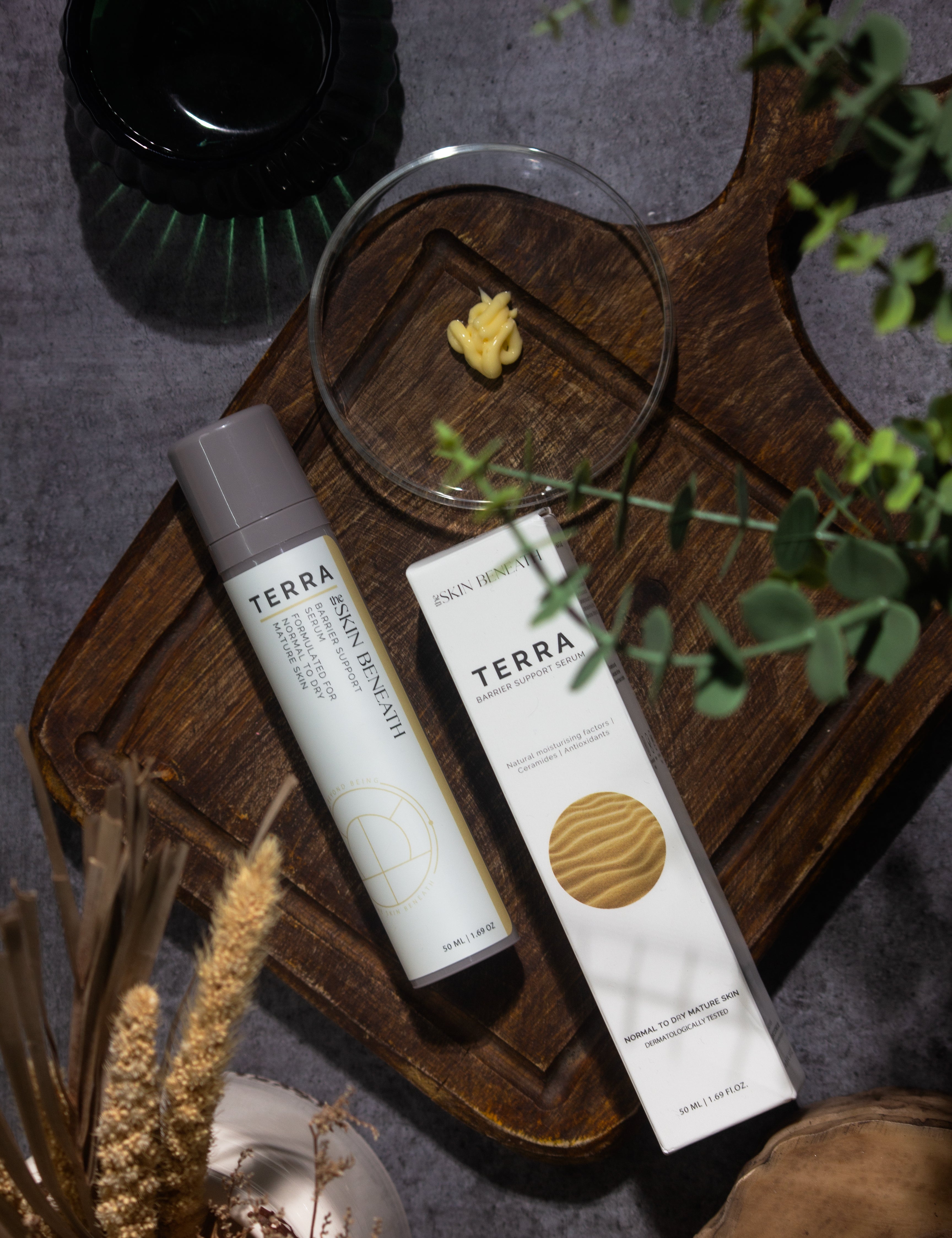 Terra barrier-repair serum bottle on vintage wooden tray with moody shadows, captured as part of an emotional skincare ritual