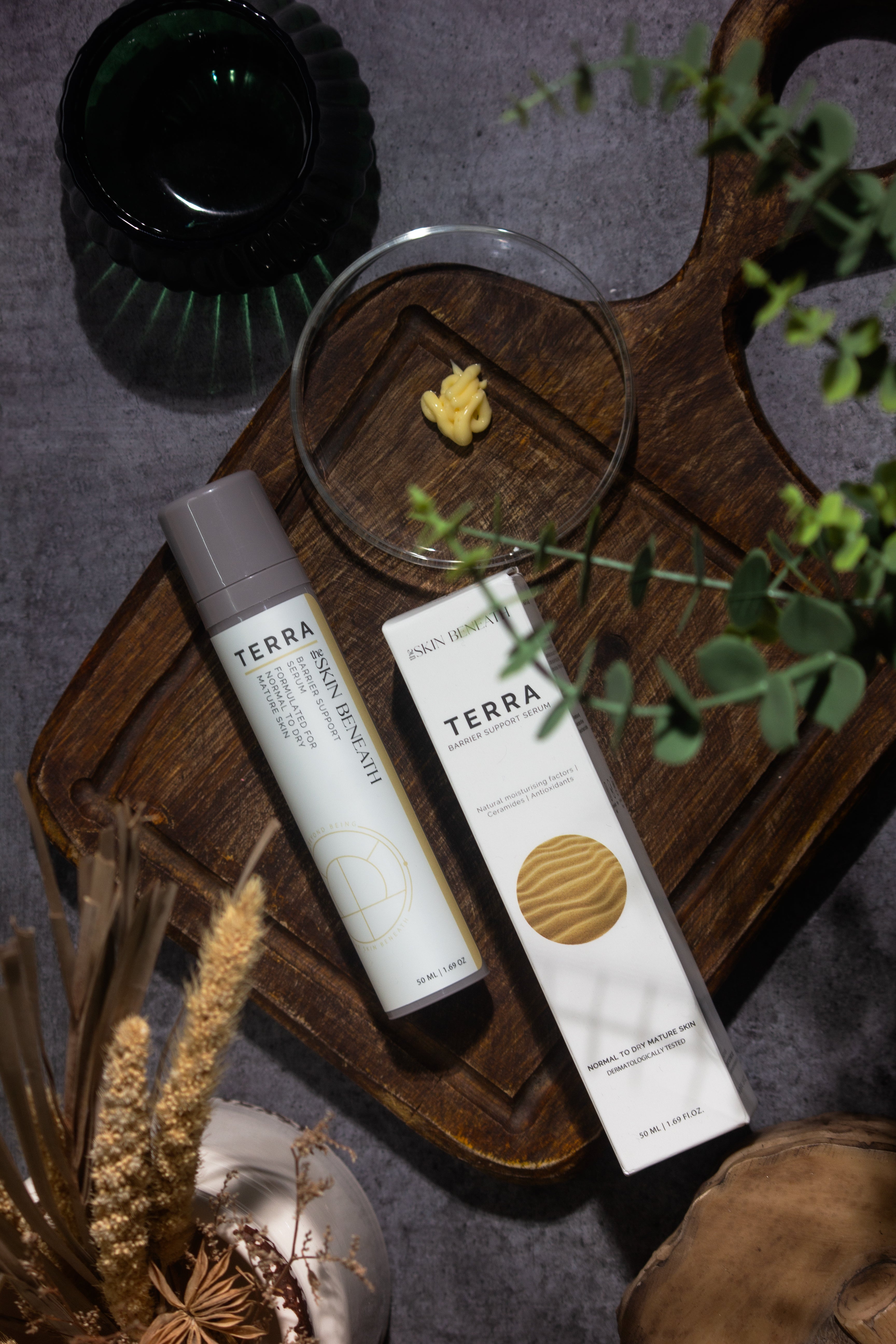 Terra barrier-repair serum bottle on vintage wooden tray with moody shadows, captured as part of an emotional skincare ritual